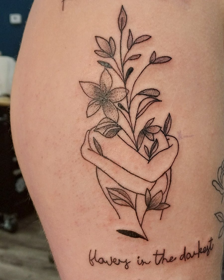 Fine-line floral tattoo with hand-lettered script, upper arm