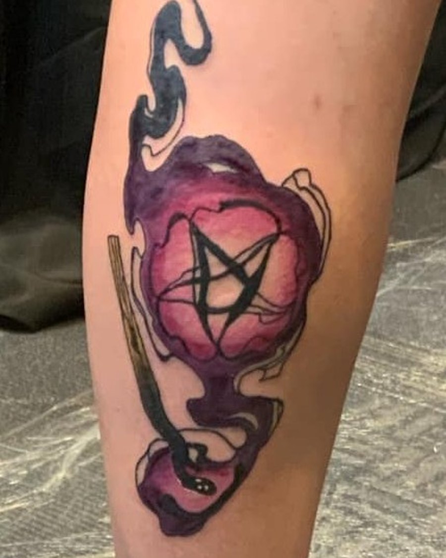 Colour tattoo of a candle and pentacle in purple and pink, calf